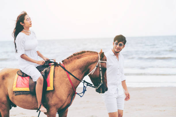 istock Young couple goes horse riding on tropical beach. 1056986320