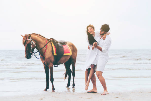 istock Young couple goes horse riding on tropical beach. 1056986404
