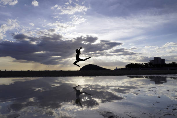 istock Jumping young girls with reflection on the beach 1056987920