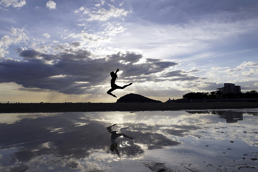 Silhouette of a young women on a sea beach. jumping young girls with reflection on the beach.
