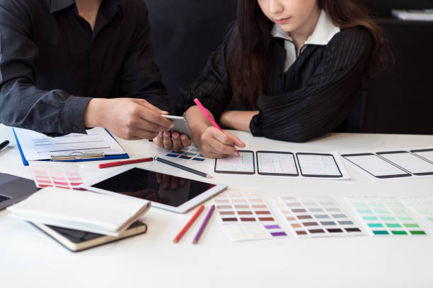 istock Creative designer team hands sketching of screens for mobile responsive website development with UI/UX. Developing wireframe sketch layout design mockup on smartphone screen. 1056990530