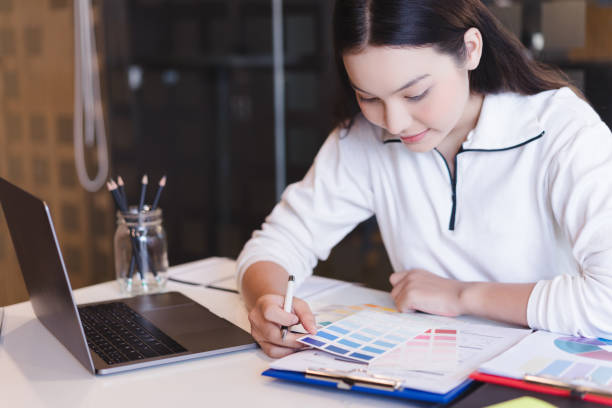 istock Young designer working with color samples for selection on office desk, Architects choosing color samples for design project,creative graphic design working desk. 1056991268