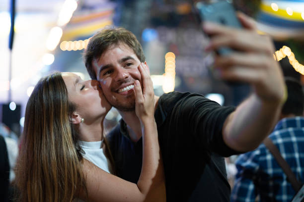 istock Young Couple Taking a Selfie at Party 1056993430