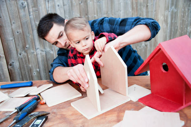 Father and Son Making a Birdhouse Father and son focus on building the perfect birdhouse for their bird visitors. nesting box stock pictures, royalty-free photos & images