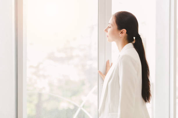 istock Business women wearing white suit standing looking out window 1057002832