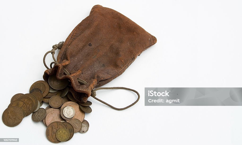 Worn leather purse spilling coins out onto white countertop A spilt purse of old coins Coin Stock Photo