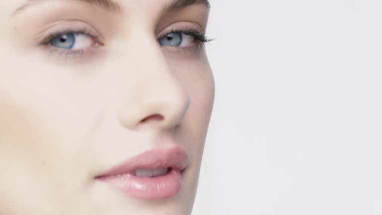 Portrait of beautiful woman with blue eyes. Close-up of young female against white background. She is having blond hair.