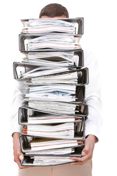 istock A man holding a large pile of binders filled with papers. 105703904