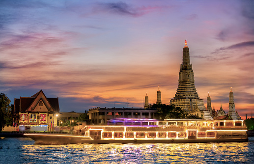 Chao Phraya River Cruise Boat with Temple of the Dawn, Wat Arun, at Sunset in Background, Horizontal