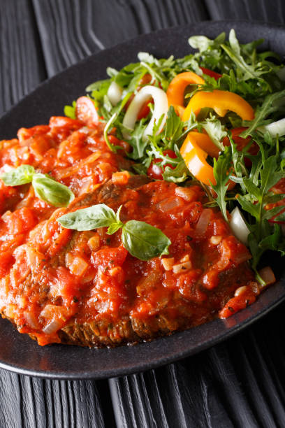 istock Beef steak with pizzaiola sauce and fresh salad close-up. vertical 1057061154