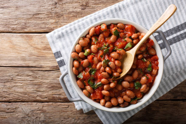 fagioli di mirtillo in stufato o borlotti in salsa di pomodoro con erbe da vicino in una ciotola. vista orizzontale dall'alto - bean foto e immagini stock