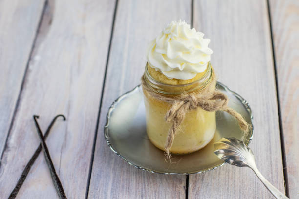 Baked pudding made from egg yolks in jar with whipped cream and vanilla pod stock photo