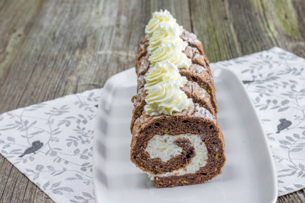 Chocolate roulade filled with whipped cream on white tray stock photo