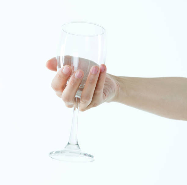 Woman hand holding empty wine glass on white background.