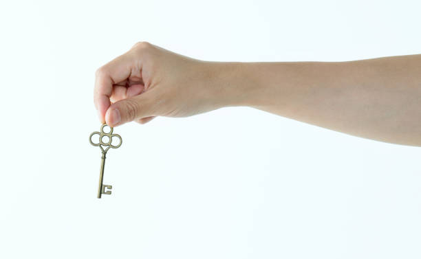 istock Woman hand holding old key on white background 1057067016