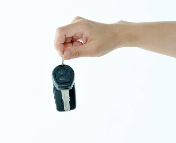 Woman hand holding a car key on white background.