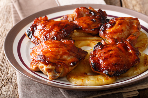 Hawaiian grill spicy chicken thighs huli huli with pineapple closeup on a plate. horizontal