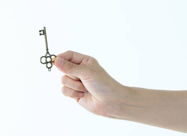 istock Woman hand holding old key on white background 1057067138