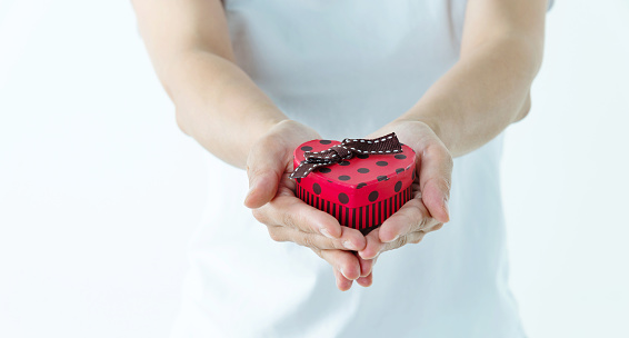 Woman hands holding a gift box on white background.