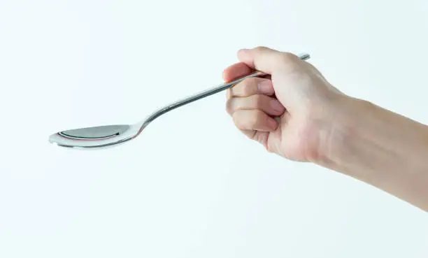 Woman hand holding a spoon on white background.