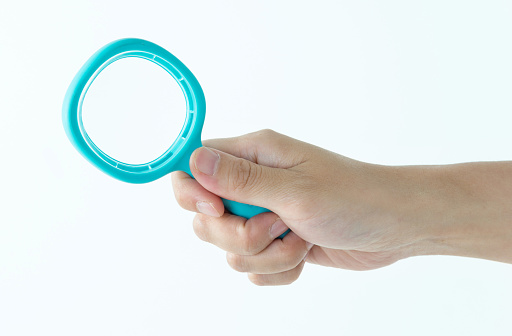 Woman hand holding magnifying glass on white background.