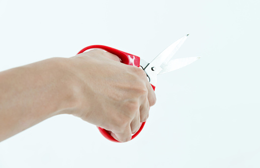 Woman hand using scissors on white background.