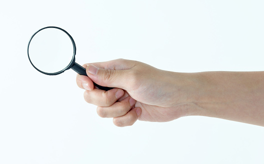 Woman hand holding magnifying glass on white background.