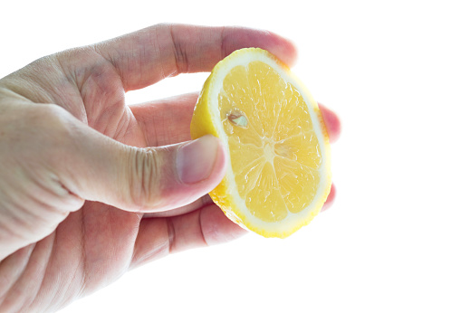 Hand squeezing lemon slice on white background.