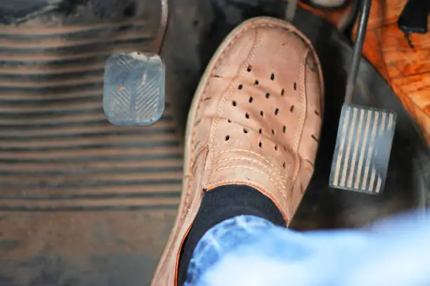 Photo of Mans feet pushing on the accelerator of automobile
