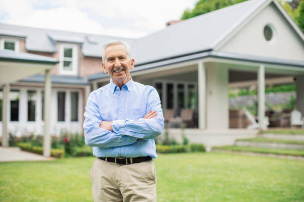 istock Senior man with arms crossed against house 1057078206