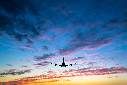 Colorful bright sunset with flying airplane silhouette