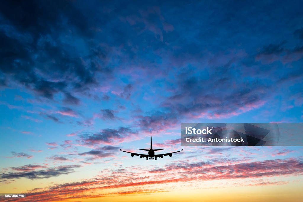 Colorful bright sunset with flying airplane silhouette Airplane Stock Photo
