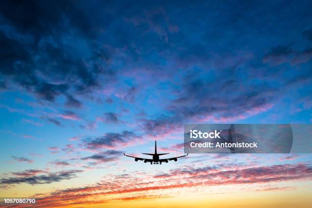 Colorful Bright Sunset With Flying Airplane Silhouette Stock Photo - Download Image Now