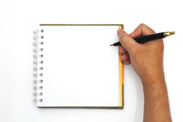 istock Hand holding a black pen writing on a notebook with horizontal lines, white background. 1057087800
