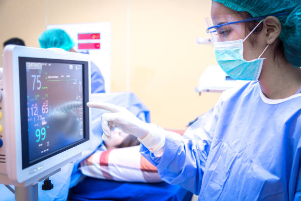 Female surgeon using monitor in operating room. Female surgeon using monitor in operating room. intensive care unit stock pictures, royalty-free photos & images