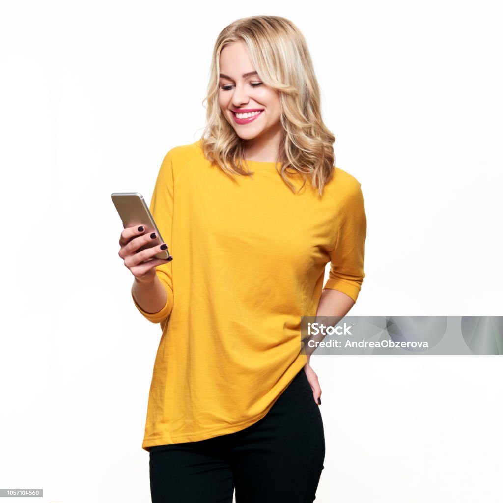 Hermosa mujer sonriente mirando su teléfono móvil. Mujer enviar mensajes de texto en su teléfono, aislado sobre fondo blanco. - Foto de stock de Una sola mujer libre de derechos