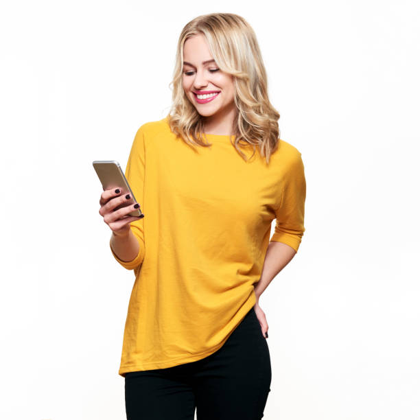 Gorgeous smiling woman looking at her mobile phone. Woman texting on her phone, isolated over white background. stock photo