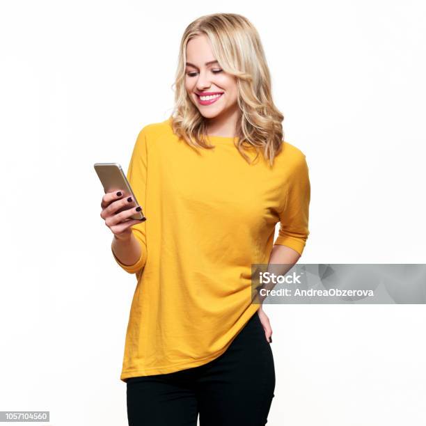 Gorgeous Smiling Woman Looking At Her Mobile Phone Woman Texting On Her Phone Isolated Over White Background - Fotografias de stock e mais imagens de Só Uma Mulher