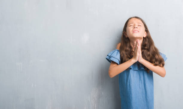 istock Young hispanic kid over grunge grey wall begging and praying with hands together with hope expression on face very emotional and worried. Asking for forgiveness. Religion concept. 1057104624