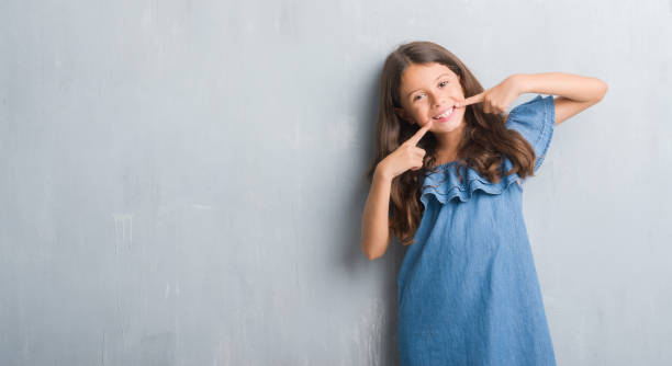 Young hispanic kid over grunge grey wall smiling confident showing and pointing with fingers teeth and mouth. Health concept. Young hispanic kid over grunge grey wall smiling confident showing and pointing with fingers teeth and mouth. Health concept. oral care in kids stock pictures, royalty-free photos & images