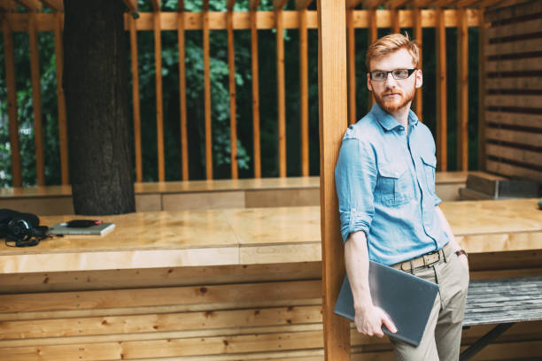 istock Man in light blue with a laptop standing by a wooden post. 1057108534