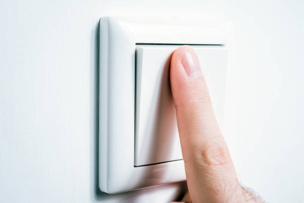 Male Finger Touching A Light Switch To Turn The Light On Or Off stock photo