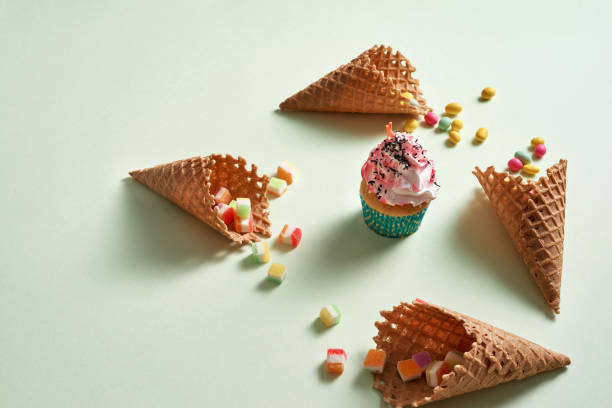 istock Round frame of assorted candy and waffle cones with cupcake on green background. Dessert concept. 1057114280