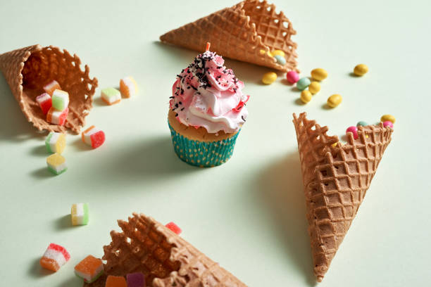 istock Round frame of assorted candy and waffle cones with cupcake on green background. Dessert concept. 1057114322