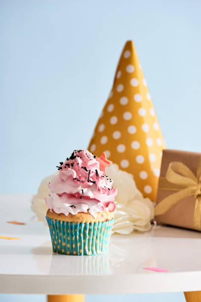 istock Birthday party background with cupcake, party hat and present 1057114434