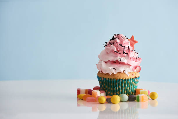 istock Cupcake with pink cream icing with candie on table 1057115578