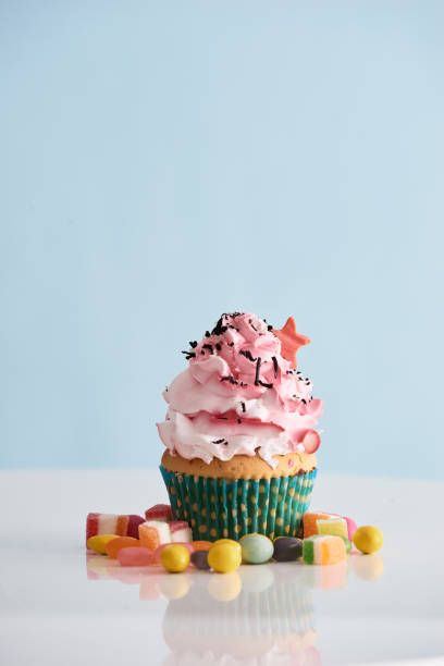 istock Cupcake with pink cream icing with candie on table 1057115600