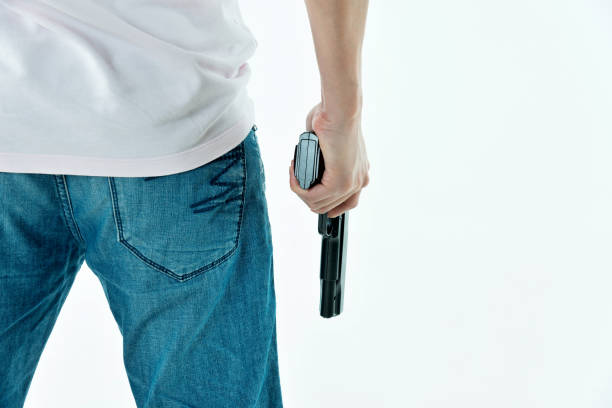 Threat of firearms. Muzzle of gun in man's hand is pointed at camera. Male criminal holds revolver on black background. Attack or defense.