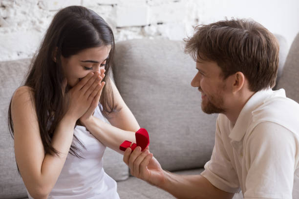 istock Happy young man propose to his girlfriend sitting on sofa 1057126268