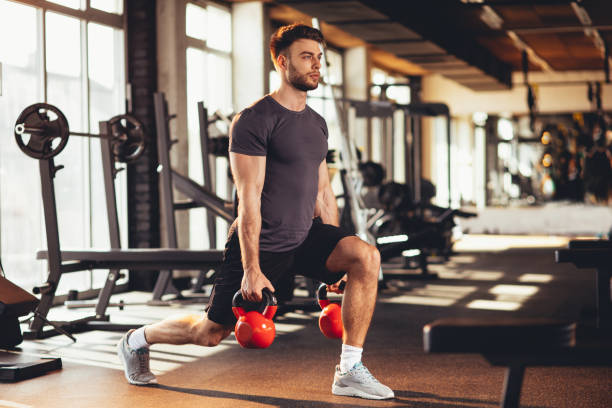 entraînement de jambes bel homme avec kettlebell dans le gymnase - gymnase photos et images de collection